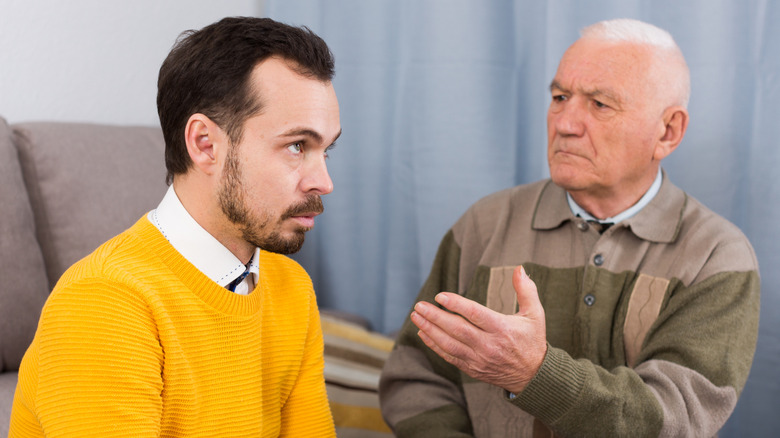 A millennial man in a yellow shirt being scolded by a boomer.