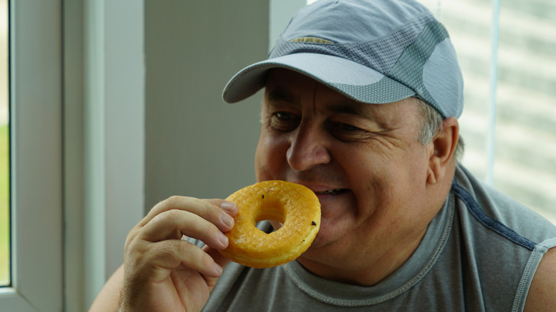 Senior man smiling while eating a dougnut