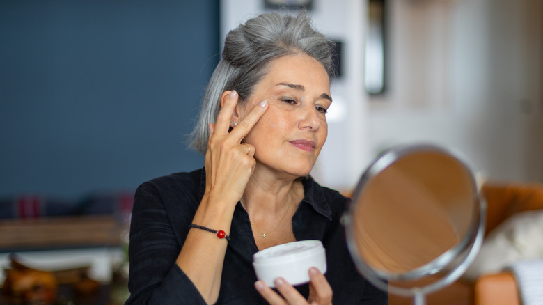 Woman applying cream to her face