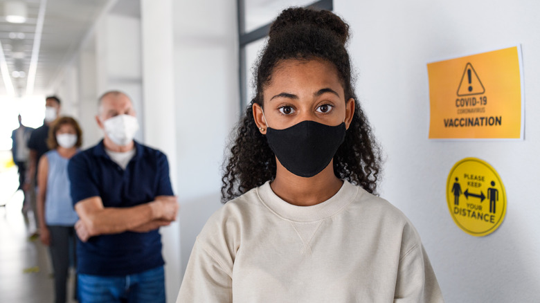 Girl with face mask waiting for COVID-19 vaccination