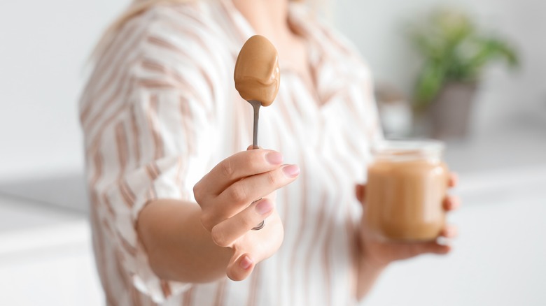 Woman's hand holding spoonful of peanut butter