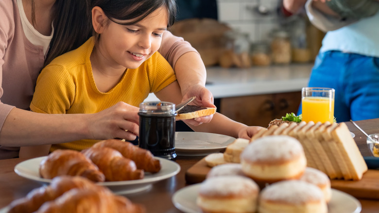 adult adding spread to child's bread