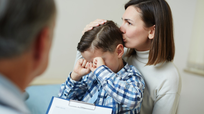 Mom kissing crying son at doctor's office