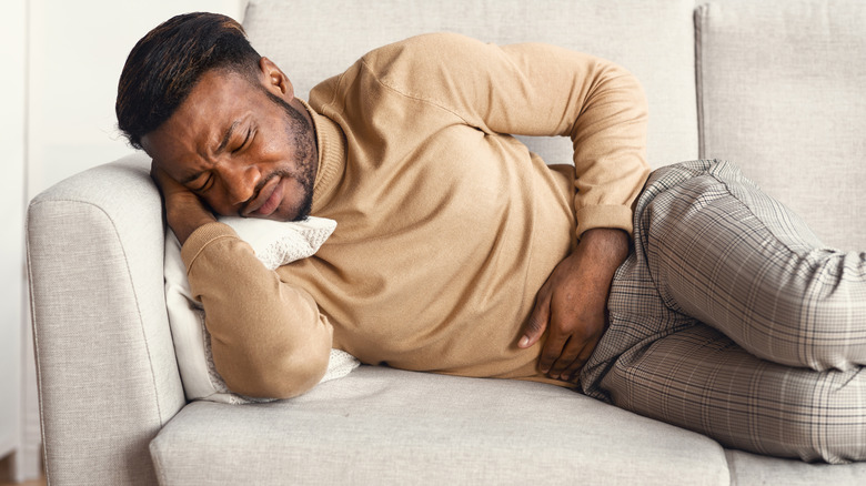 Man wincing in pain on couch