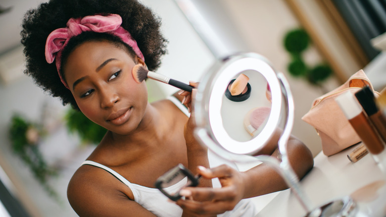 woman applying blush on her cheeks