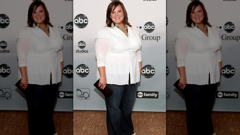 Melissa McCarthy smiling in a white top and jeans