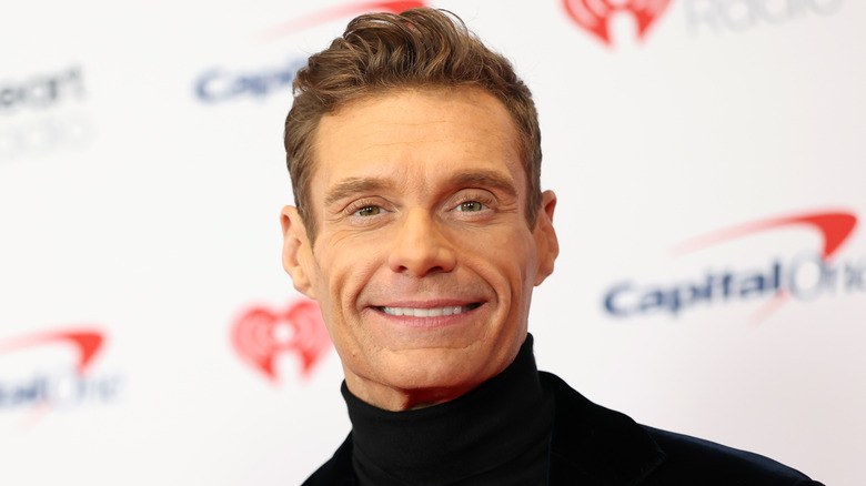 Ryan Seacrest posing in 2025 at a celebrity event for a radio station