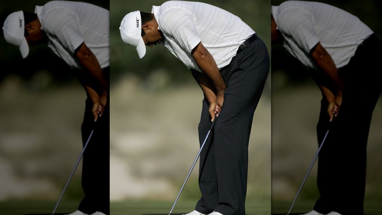 Tiger Woods holding onto his knee while playing golf