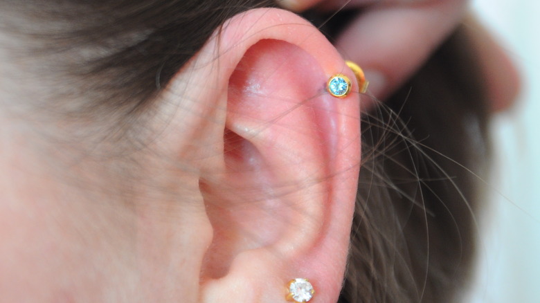 Close up on hand touching ear cartilage piercing