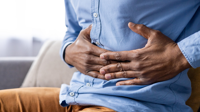 man with hands on stomach in discomfort