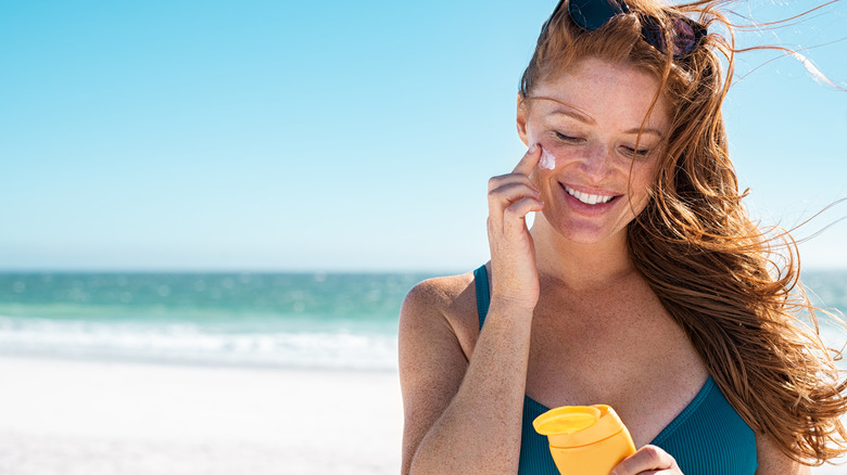 Woman at beach applying sunscreen to face