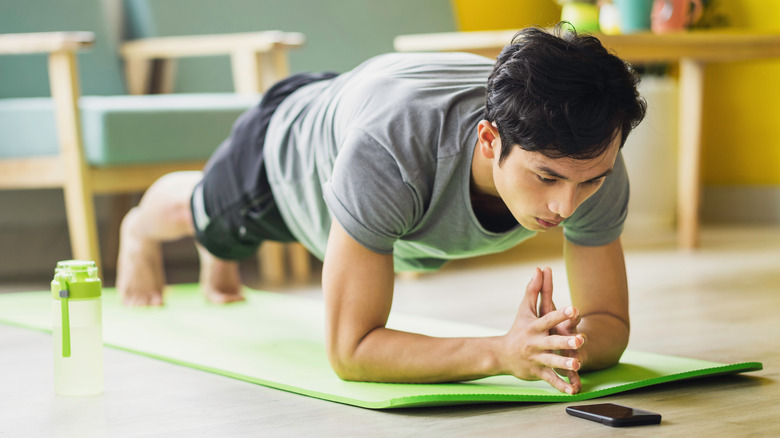 man doing a plank while looking at his phone