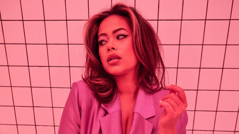 Catie Li sitting on a bench in a pink blazer