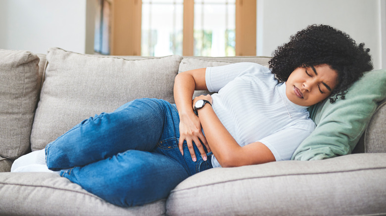 Woman laying on couch with stomach pain