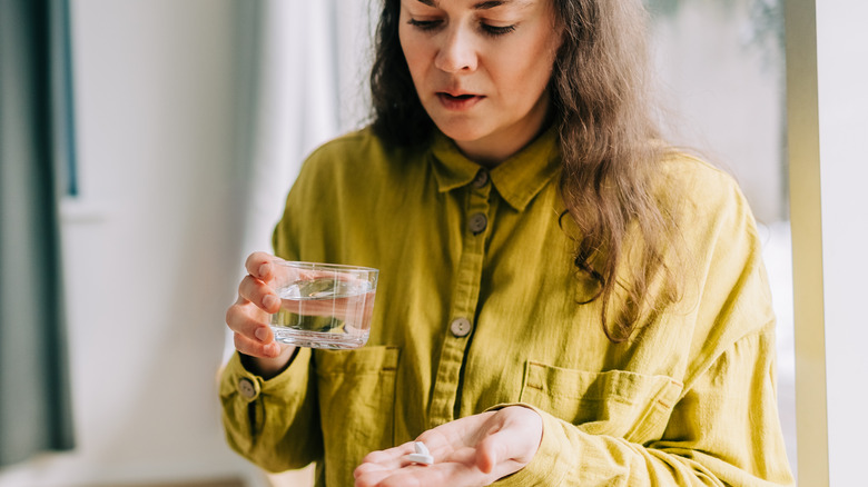 A woman holding medication in one hand and pills in another