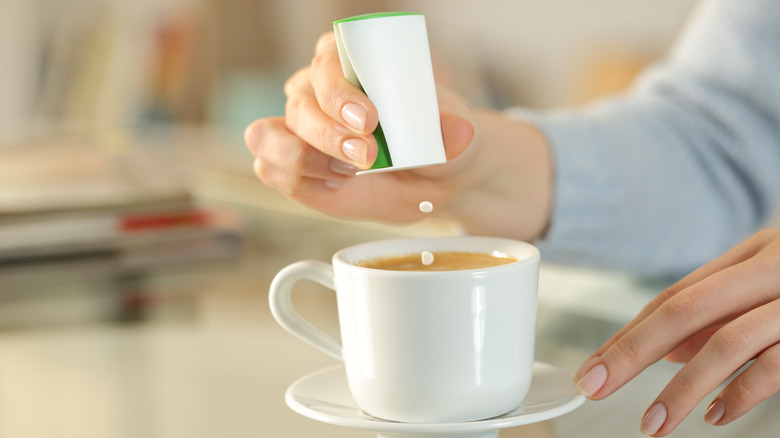woman adding sugar substitute to her coffee