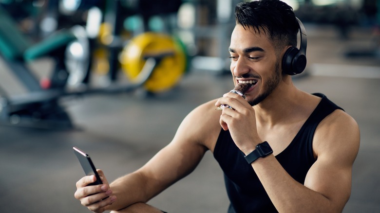 Man eating protein bar in the gym while taking a selfie