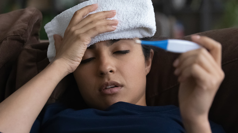sick woman in bed with thermometer