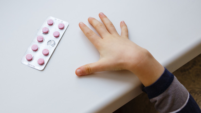 Child hand reaching for medication pack