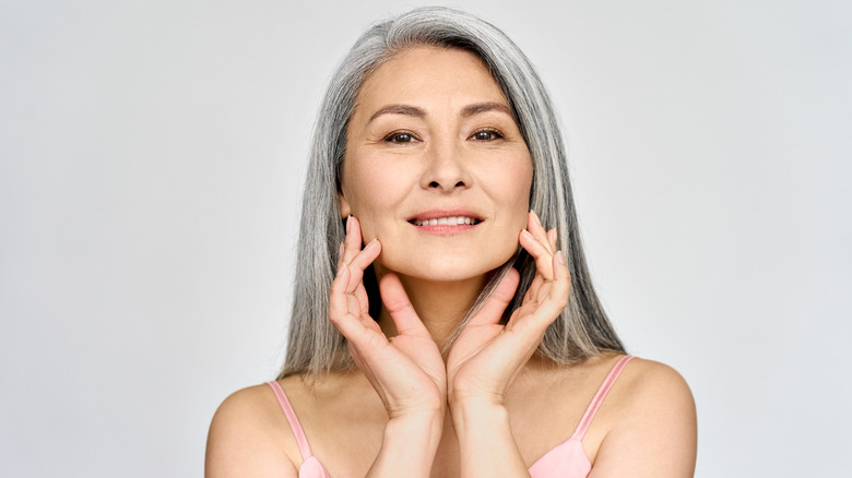 elderly woman using pressure massage on face