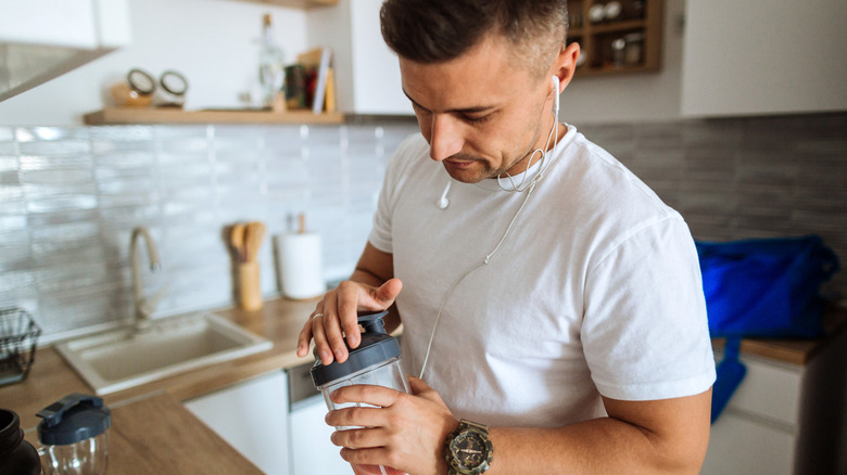man fixing a whey protein shake in a shaker