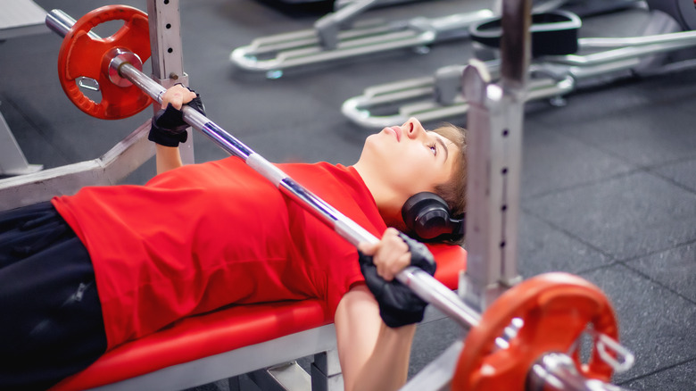 A young man uses the bench press at the gym