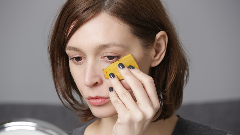 Woman placing banana peel on face