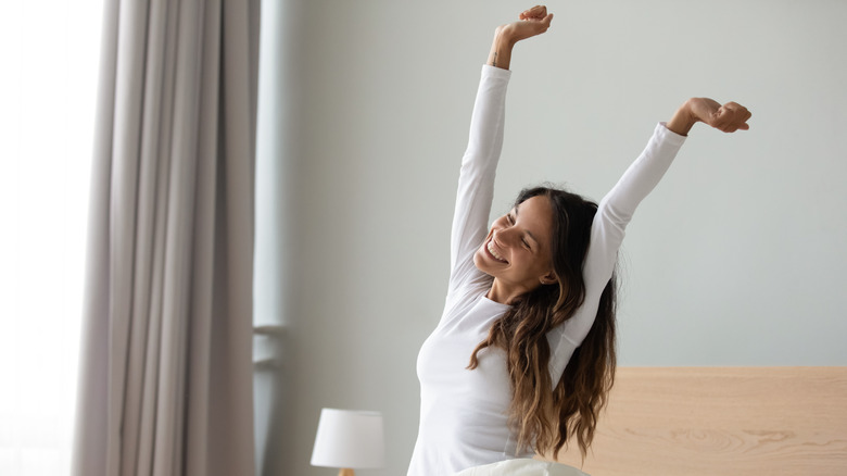 woman waking up with arms in air