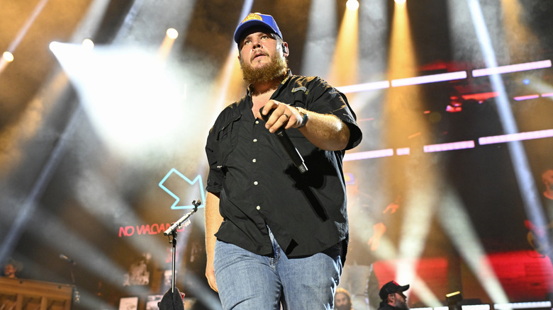Luke Combs holding a microphone walking on stage