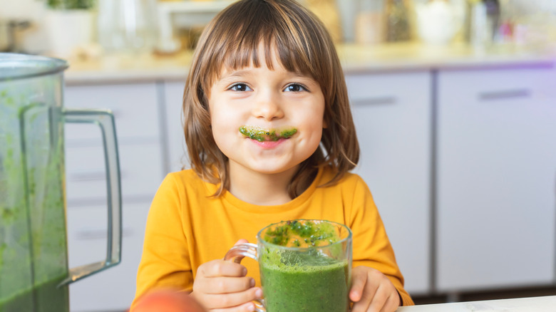 Young child enjoying green smoothie
