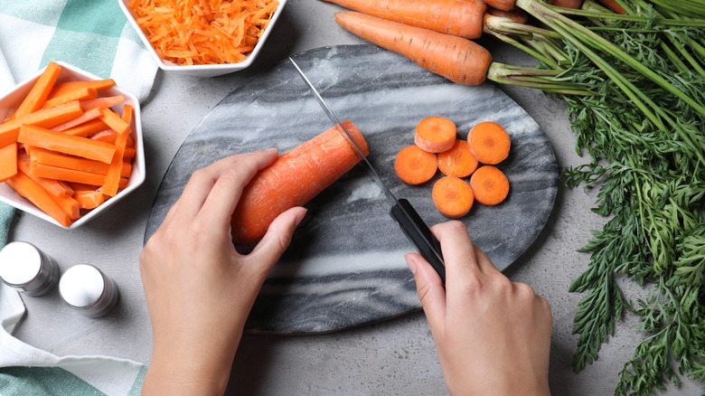 woman prepping carrots on a cutting board