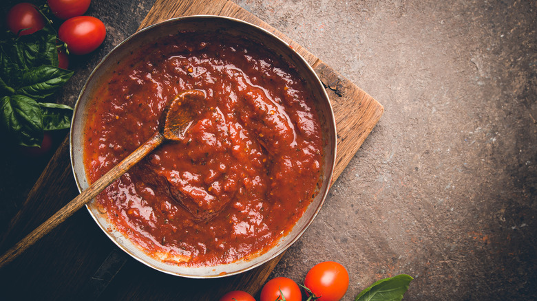 a large saute pan of tomato sauce and raw tomatoes surrounding it