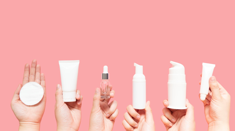 People holding up different bottles of skincare products