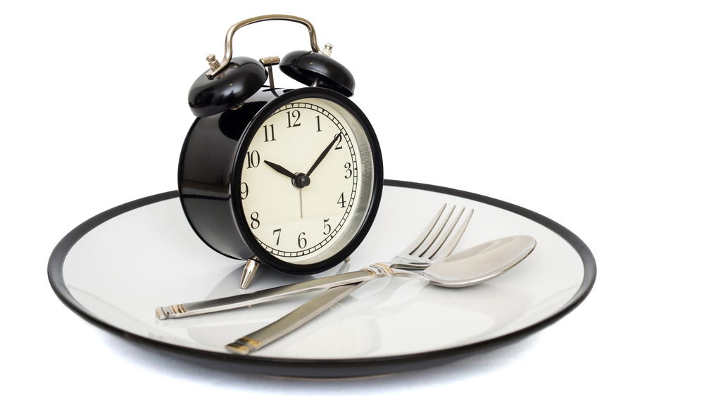 Alarm clock, silverware sitting on plate