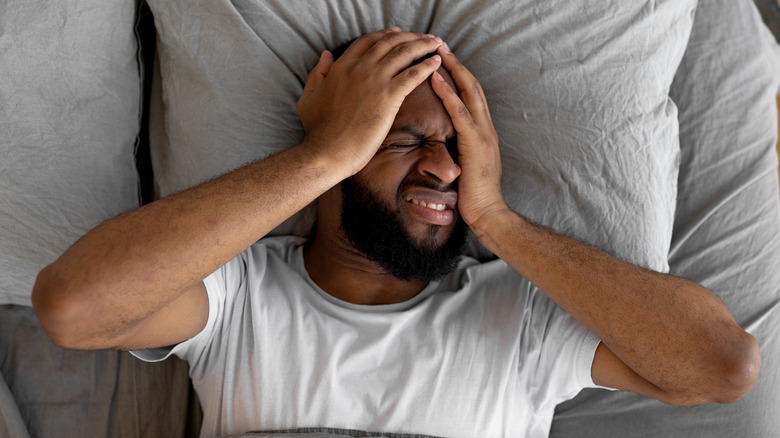 man in bed holding head