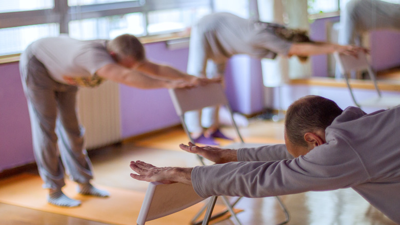 people practicing downward dog yoga pose with a chair