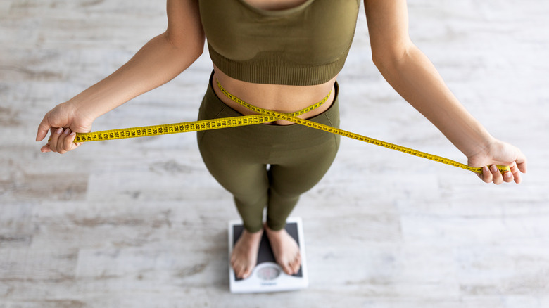 A woman weighing and measuring herself