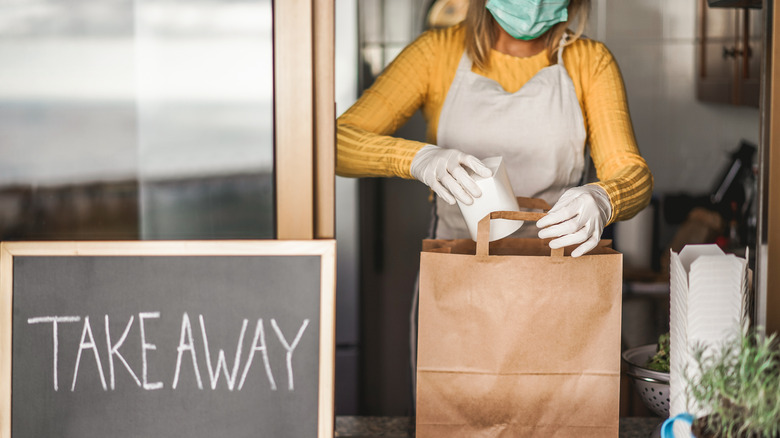 Someone prepares food for a takeout order