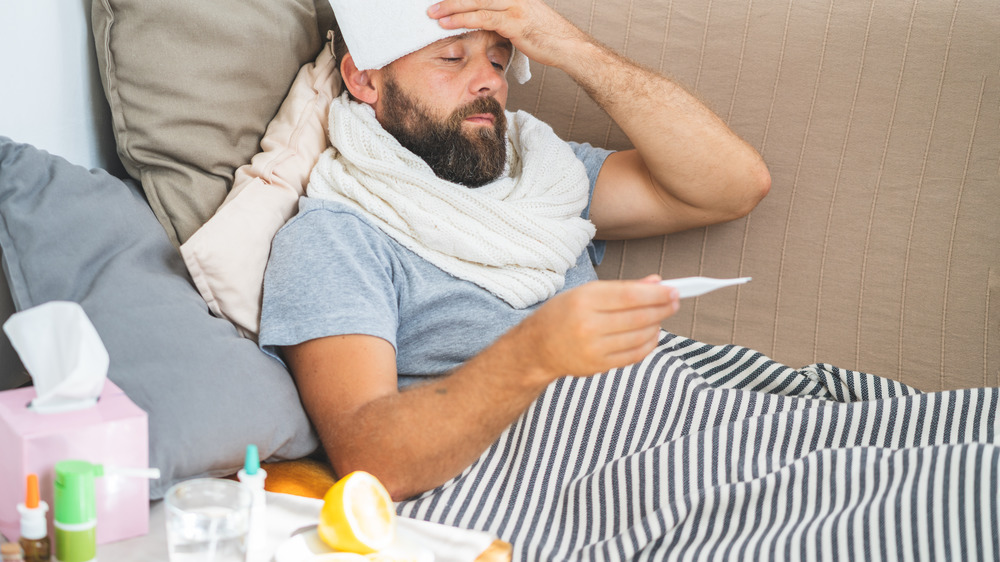 Man holding cloth on forehead and checking temperature