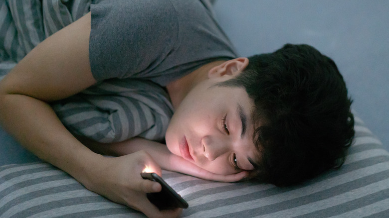 Teen looking at phone in bed