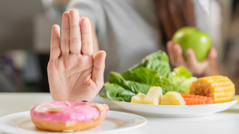 Woman holding hand up to donut