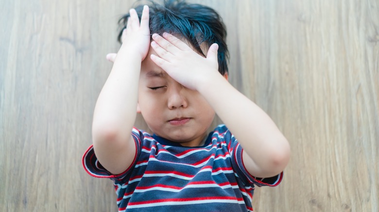 child holding his head