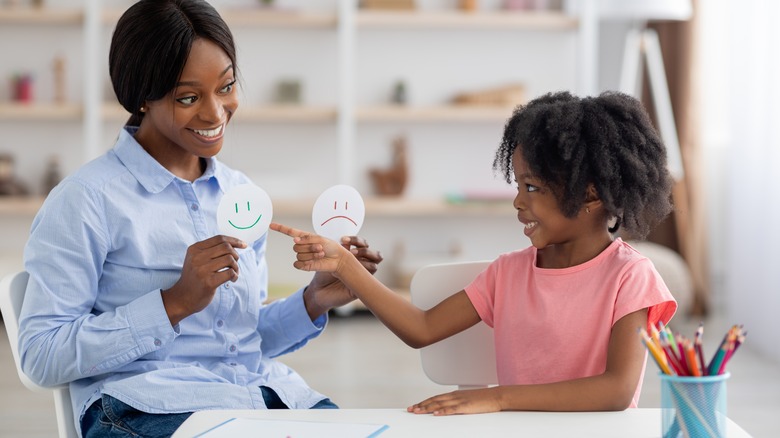 teacher shows child happy and sad faces 