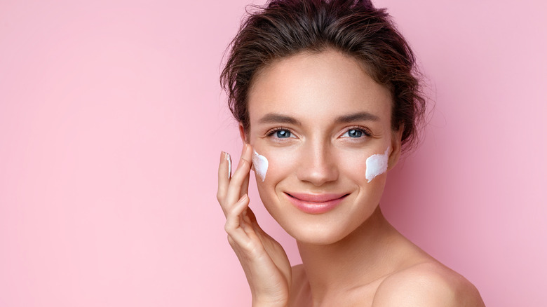 headshot of woman applying face cream