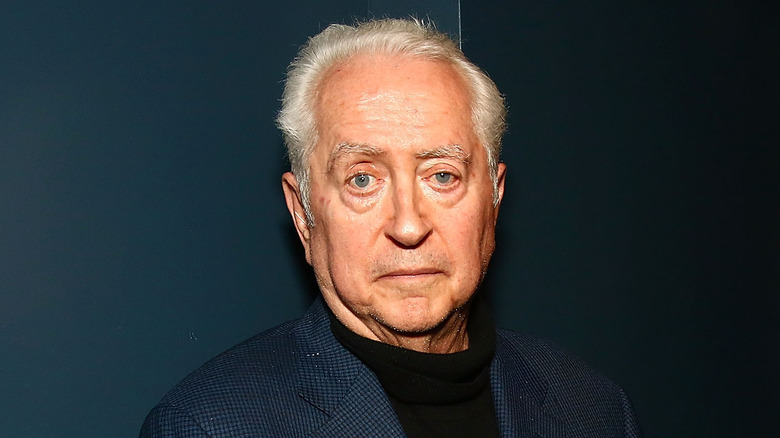 Robert Downey Sr. stands in front of a dark background