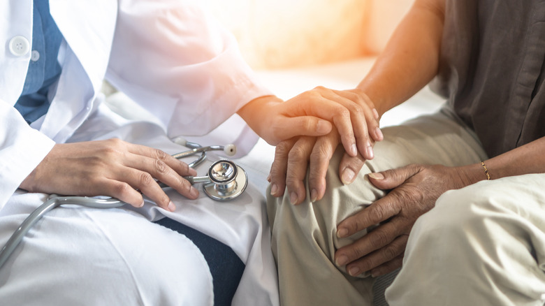 A doctor holds the hand of someone with Parkinson's disease