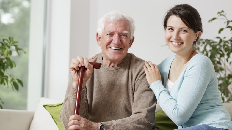 A smiling woman sits by a smiling elderly man