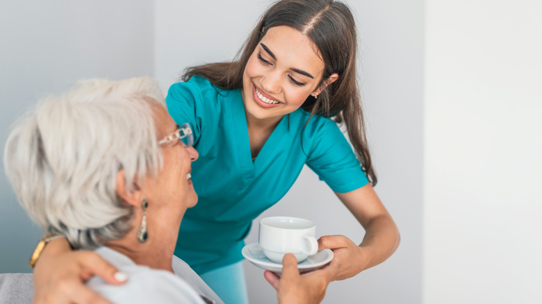A caregiver helps an elderly woman