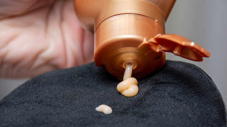 hand squeezing self-tanning lotion onto special glove