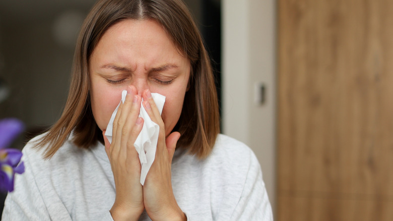 woman blowing her nose due to an allergic reaction
